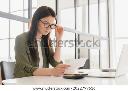 Successful young business woman freelancer manager accountant counting funds, savings, money using calculator in office. Woman paying domestic bills, economizing. Economy and finances concept Royalty-Free Stock Photo #2022799616