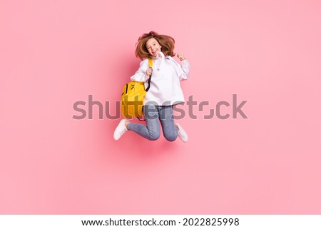 Full length body size girl jumping up wearing yellow rucksack gesturing like winner isolated pastel pink color background