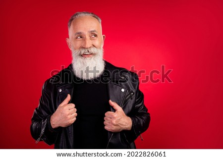 Photo of curious minded cool old man look empty space think thoughts wear leather jacket isolated on red color background