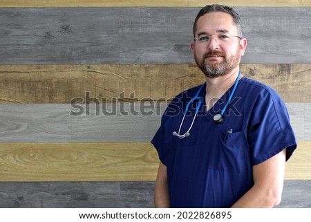 Professional mature medical doctor man, light eyes, beard with stethoscope and blue gallantdale, ready to work
