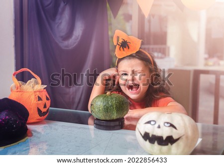 Happy child preparing pumpkins for Halloween at home at the table