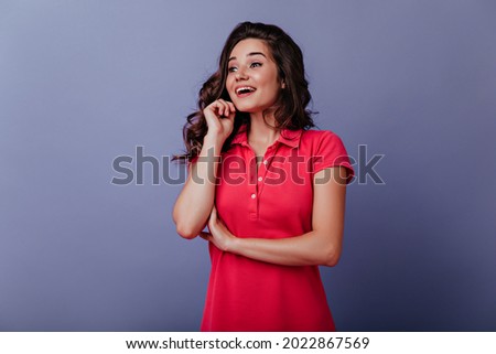 Jocund graceful woman looking away with inspired smile. Curly dark-haired girl expressing amazement.