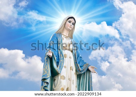 Statue of Our lady of grace virgin Mary with Bright Blue Sky and beautiful clouds with abstract colored background and wallpaper at Thailand. Royalty-Free Stock Photo #2022909134