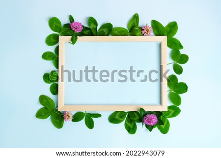 White paper frame copy space. Flat lay, blue background. With clover petals