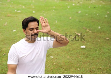 A man in a white yoga outfit practicing yoga asana in a park among greens and ducks quietly