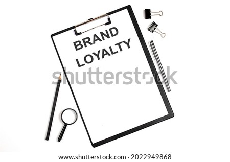 On a white background magnifier, a pen and a sheet of paper with the text BRAND LOYALTY .Business