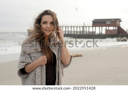 Happy smiling brunette woman portrait dressed knitted sweater, autumn outdoor photo against seascape