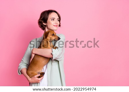 Photo of cool young lady hug dog look empty space wear grey green jacket isolated on pink color background