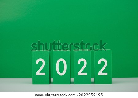 2022 numbers on white table against green background with copy space. Minimal elegant concept of New Year celebration