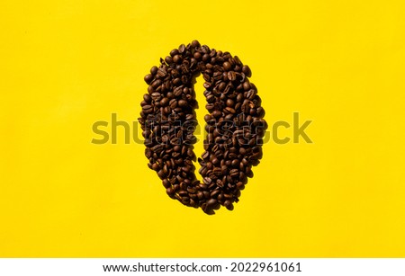Top view of coffee beans in bean shape with yellow background.