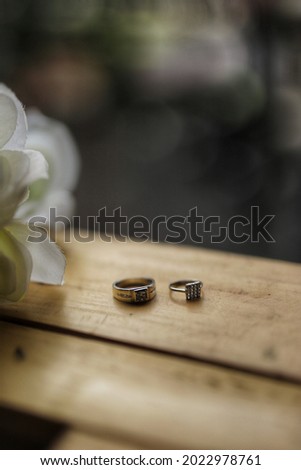 a pair of rings and flowers on a wooden background