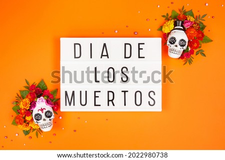 Lightbox with Dia De Los Muertos text on orange background. Day of the dead Celebration. Sugar Skull, calaverita, marigolds flowers. Traditional Mexican culture festival flyer. Flat lay, top view.