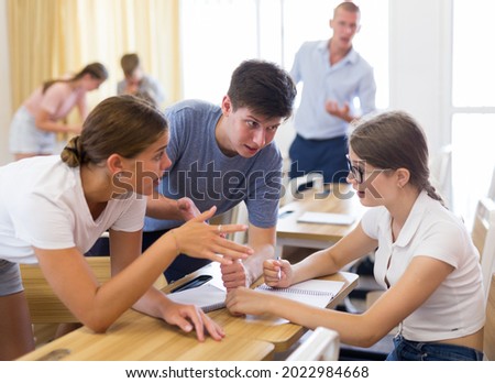 Focused teenagers working in small groups during lesson at college, discussing assignment given by teacher. Active learning concept Royalty-Free Stock Photo #2022984668