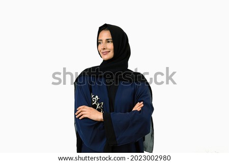 Happy Emarati women wearing Abaya doing cross arm looking far.  UAE girl in Hijab hair veil as part of cultural outfit.  Royalty-Free Stock Photo #2023002980