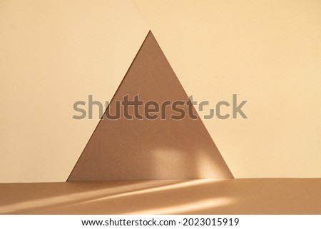 Abstract geometric textured background. Arbitrary triangle made of brown paper on beige surface. Ready-made mockup for advertising, beauty industry.