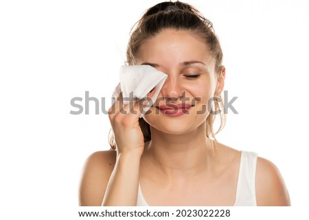 A smiling woman cleans makeup from her face with wet wipes on a white background Royalty-Free Stock Photo #2023022228