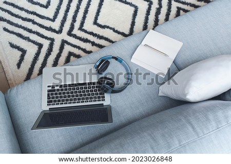 Modern laptop with headphones on sofa in room