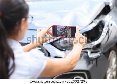 Woman agent takes pictures of damage to car after accident by smartphone Royalty-Free Stock Photo #2023027298