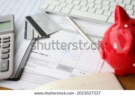 Paid words and calculator with a piggy bank on counting paper for payment closeup
