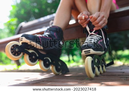Young woman puts on roller skates in park closeup Royalty-Free Stock Photo #2023027418
