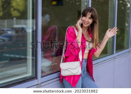 Stylish female talking by mobyle phone ,sranding over modern urban background. 