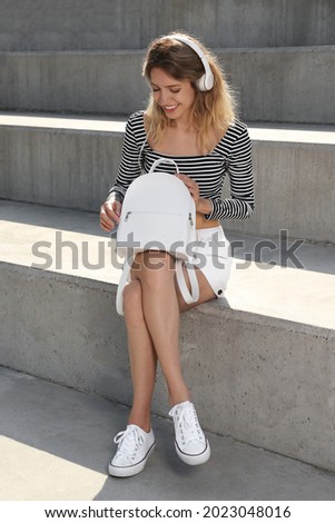 Young woman with stylish backpack on stairs outdoors