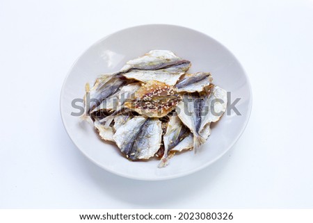 Dried fish with sesame seeds in white plate on white background.