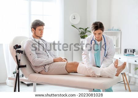Doctor putting broken leg of young man in plaster Royalty-Free Stock Photo #2023081028