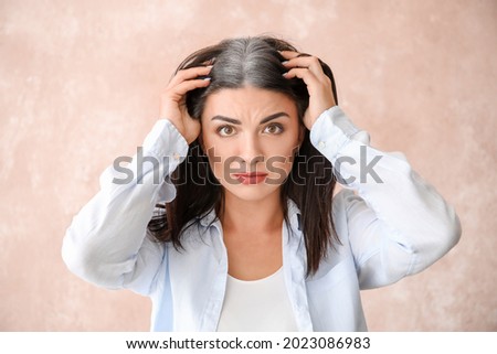 Stressed woman with graying hair on color background Royalty-Free Stock Photo #2023086983