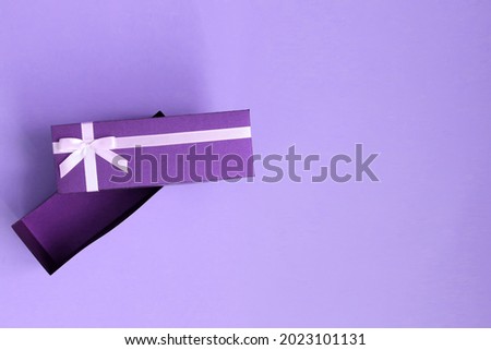 Very peri toned gift box with ribbon and greeting list on a purple background. Copy space for text. Selective focuse. Invitation card