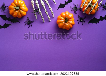 Halloween flat lay composition with pumpkins, bony hands, spiders, bats on purple background. Happy halloween banner mockup. Royalty-Free Stock Photo #2023109336