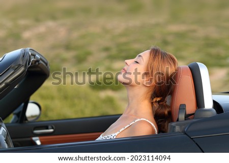 Profile of a woman breathing fresh air in a convertible car Royalty-Free Stock Photo #2023114094