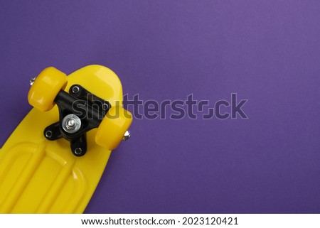 Skateboard on purple background, top view. Space for text