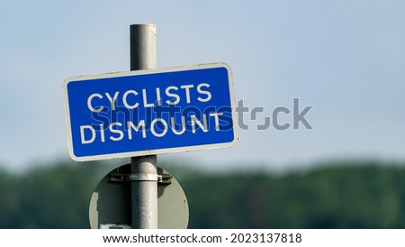 A blue cyclists dismount sign in a park