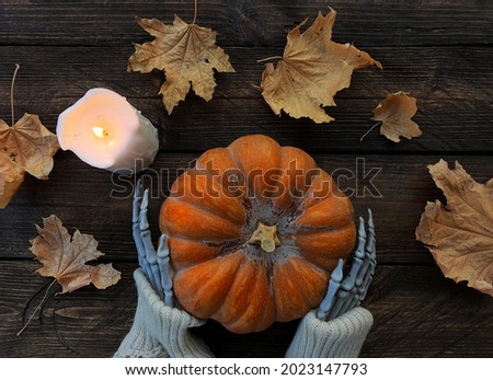 skeleton hands hold a beautiful orange pumpkin
