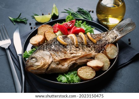Tasty homemade roasted crucian carp served on black table. River fish Royalty-Free Stock Photo #2023150475
