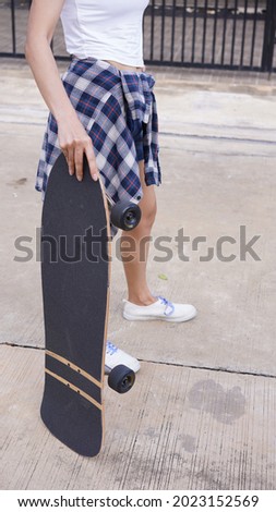 Surf Skate, extreme sport with four wheels on board sliding on street or pump track. Famous teenager sport in urban. Woman in short denim pant with shirt at her waist on surf skate board on street.