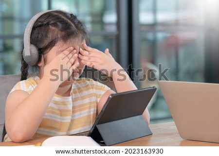 Asian girl covered her eyes from digital eye strain, girl used tablets too much to cause eye strain,eyes problems from using a tablet,education and vision problems. Royalty-Free Stock Photo #2023163930