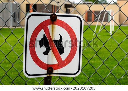 No Dogs Allowed sign without text on a schoolyard fence.