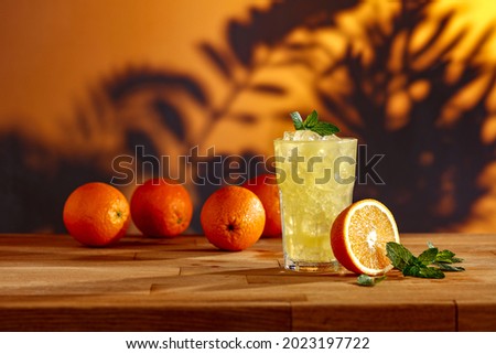 Orange juice with ice on a wooden table on a tropical day 