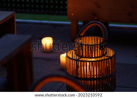 Portable outdoor garden lantern spending warm light on a balcony lounge Royalty-Free Stock Photo #2023210592