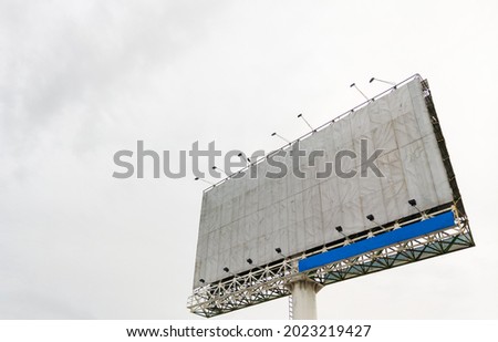 The blank billboard for the advertisement near the intersection in the city, white sky from the cloud after the rain, front view with the copy space.