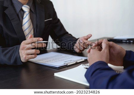 Close up interviewer interview candidate apply for a job at the meeting room in the office. Image of a man hand pointing at a document about applying for a job to the supervisor at the office.