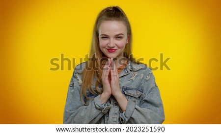 Sneaky cunning teen stylish girl with tricky face gesticulating and scheming evil plan, thinking over devious villain idea, cunning cheats, jokes and pranks. Young woman on yellow studio background Royalty-Free Stock Photo #2023251590