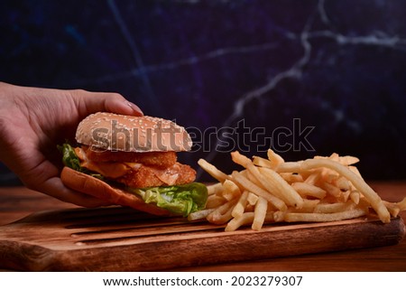 Woman holding homemade Tasty fish burger.