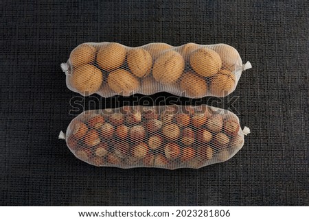 Different nuts, walnuts and hazelnuts are packed in a white grid and lie horizontally on a dark table for sale