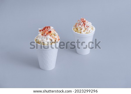 Mexican snack, two trolley, prepared esquite, corn in a cup, with chili powder on orange background, no people Royalty-Free Stock Photo #2023299296