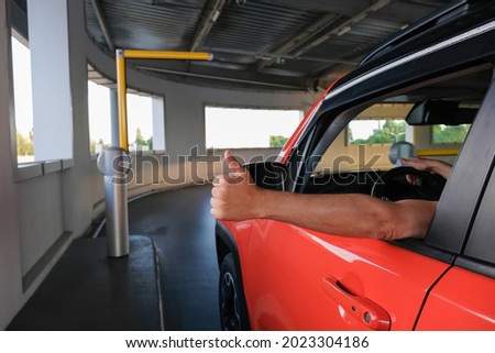 A man's hand with a thumb up near the car when entering an underground parking lot. Parking security system