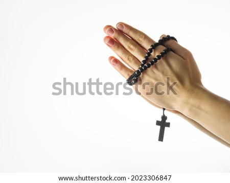 Rosary and crucifix in a female hand on a white background. Minimalism. Religion, Catholicism, spirituality, faith, meditation. There is an empty space for an inscription. Royalty-Free Stock Photo #2023306847