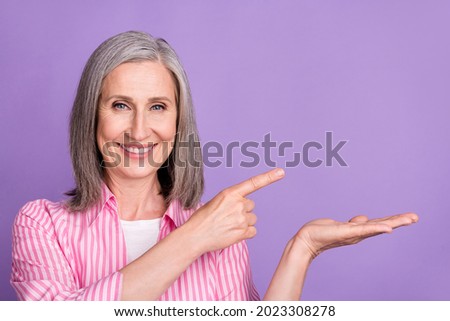 Photo of mature woman happy positive smile point finger product promo offer isolated over violet color background